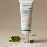 OTC version Complete No-Stress Physical Sunscreen V.3 with Mugwort and Niacinamide, displayed with a swatch of the product and fresh green leaves for a natural touch.